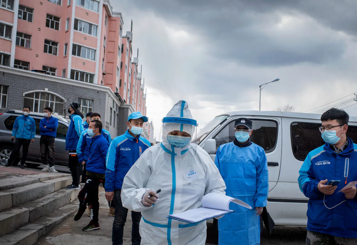 A medical worker checks notes in front of food delivery employees, who wait in line to have their nucleic acid test, at a health services center in Suifenhe, China on April 24, 2020. (STR/AFP via Getty Images)