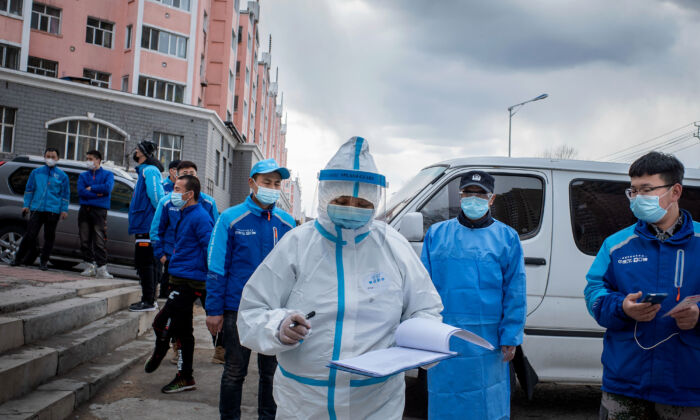 A medical worker checks notes in front of food delivery employees, who wait in line to have their nucleic acid test, at a health services center in Suifenhe, China on April 24, 2020. (STR/AFP via Getty Images)