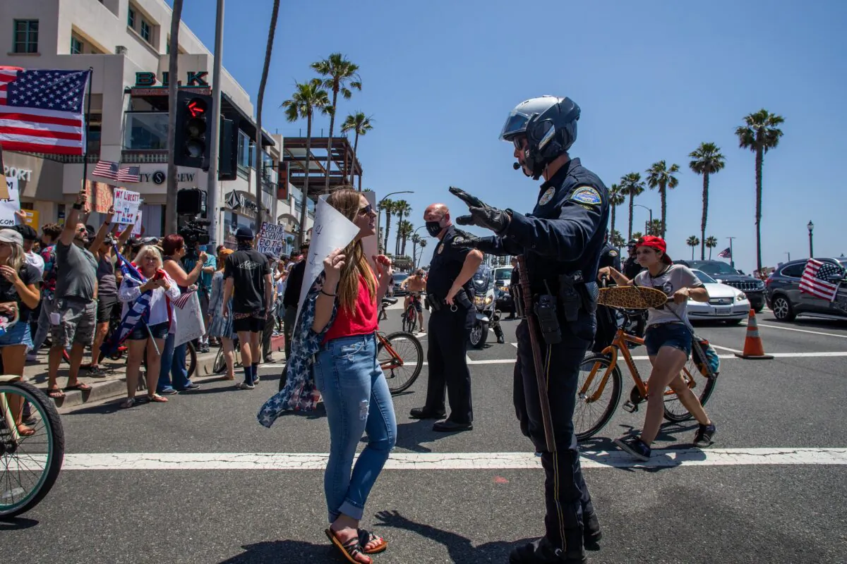 A police officer talks to a protestor at a demonstration in Huntington Beach, California on May 1, 2020. (Apu Gomes/Getty Images)