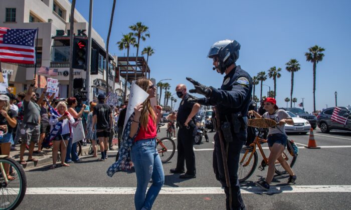 A police officer talks to a protestor at a demonstration in Huntington Beach, California on May 1, 2020. (Apu Gomes/Getty Images)