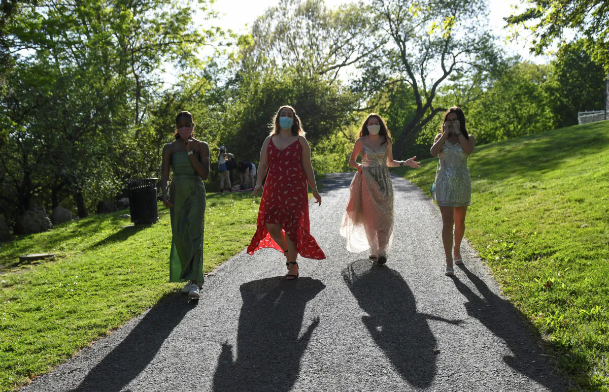 Mila Contreras-Godfrey, Katie Reisig, Gwyn McLear and Melina Bertsekas, high school seniors graduating from Beaver Country Day School, walk through Larz Anderson Park while posing for photographs in their prom dresses, in Brookline, Mass., May 22, 2020. (REUTERS/Faith Ninivaggi)