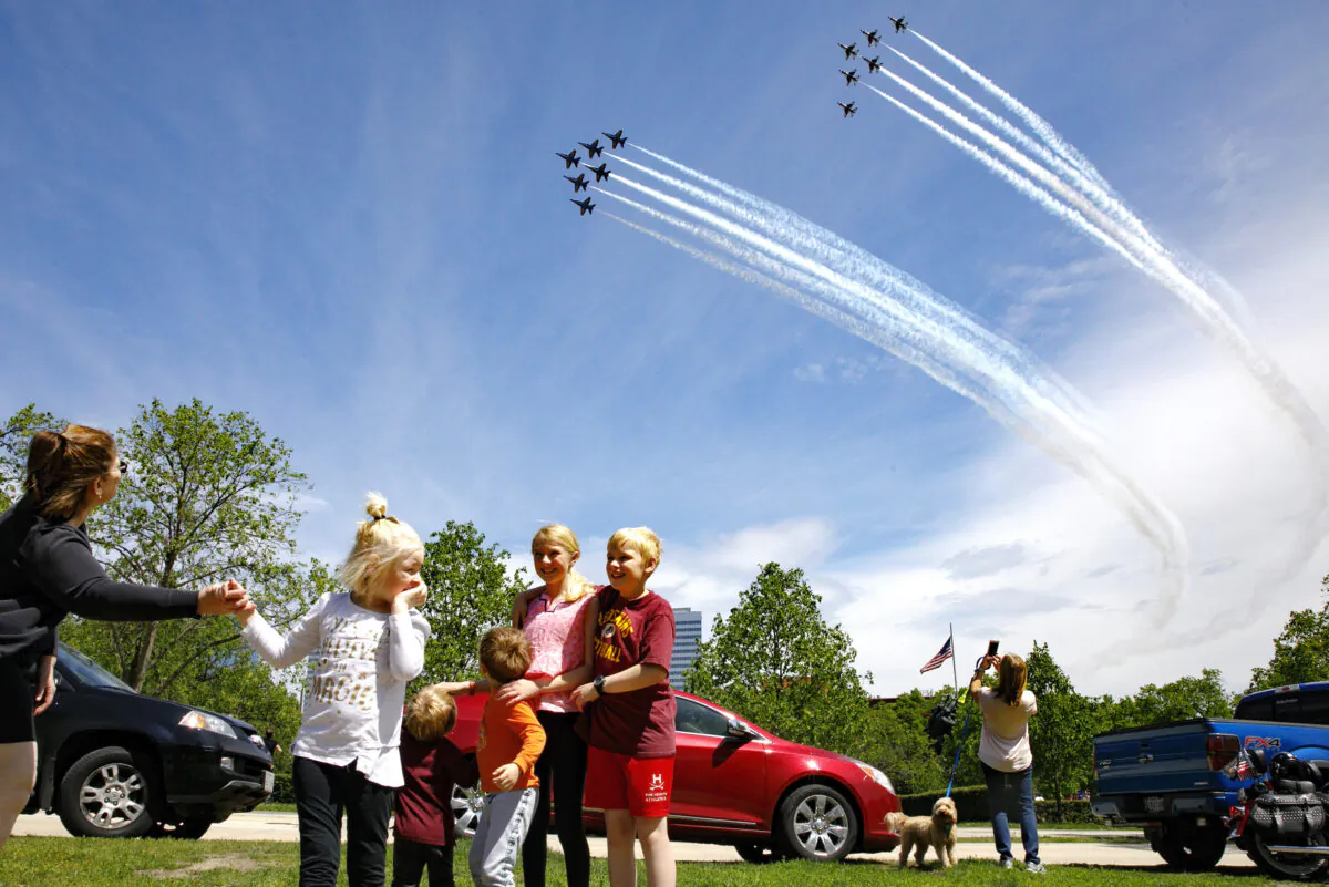 The Ferry family, from Chantilly, Va., who were in the middle of taking a family photograph, are surprised by a second fly over by the Blue Angels and Thunderbirds, in a "salute to frontline COVID-19 responders," as seen near the U.S. Marine Corps War Memorial that depicts a flag raising over Iwo Jima, in Arlington, Va., on May 2, 2020. (Jacquelyn Martin/AP Photo)
