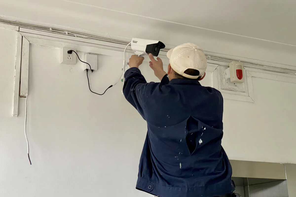 A worker adjusts a surveillance camera outside the home of a journalist placed under quarantine after he had visited Wuhan in Beijing, China on May 3, 2020. (Leo Ramirez/AFP via Getty Images)