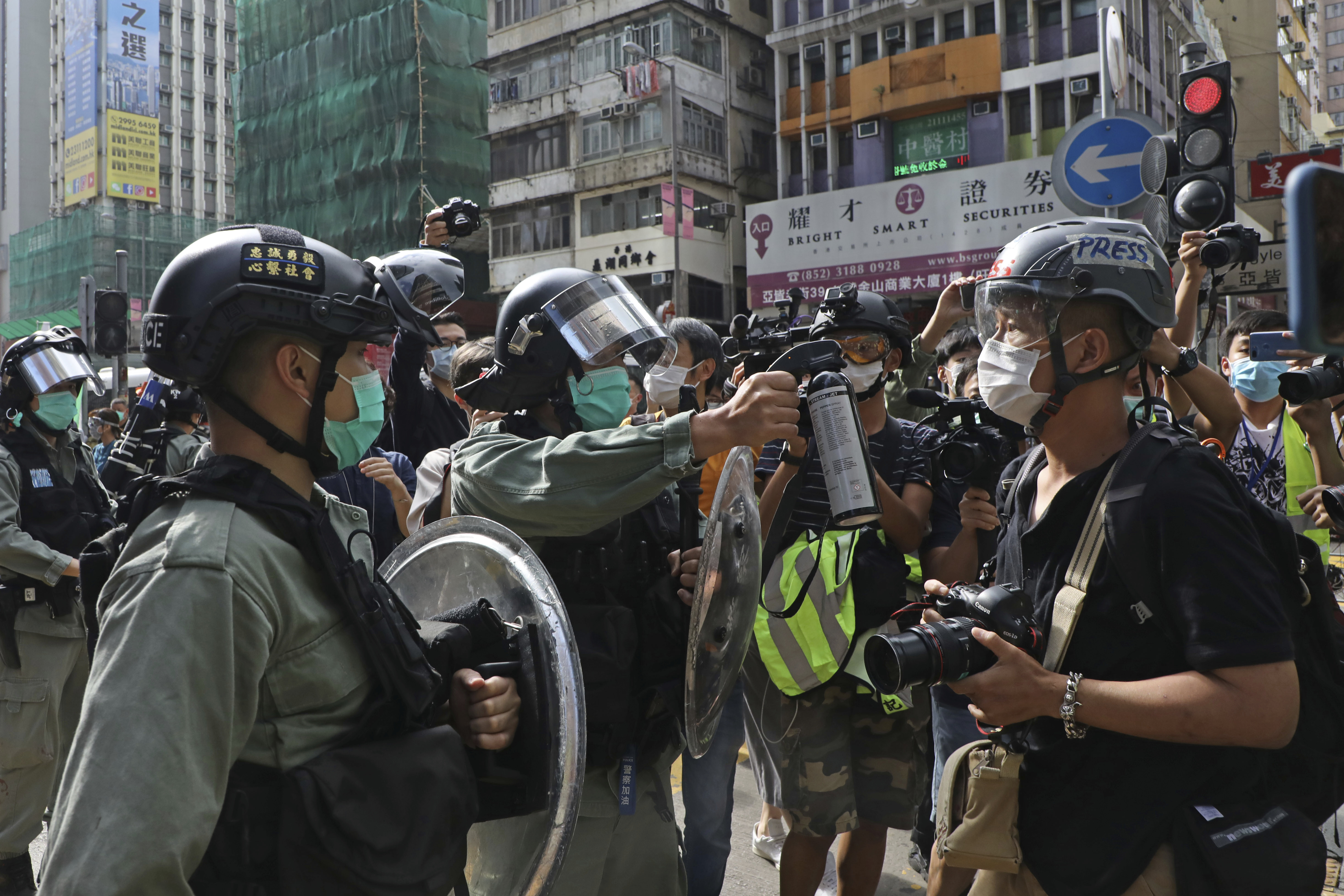 A riot police points the pepper spray to journalists