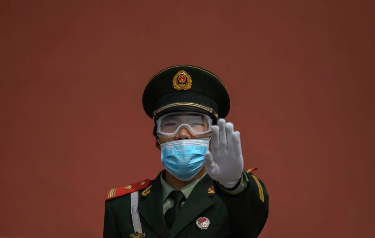 A Chinese paramilitary police officer gestures as he wears a protective mask while standing guard at the entrance to the Forbidden City as it re-opened to limited visitors in Beijing, China, on May 1, 2020. (Kevin Frayer/Getty Images)