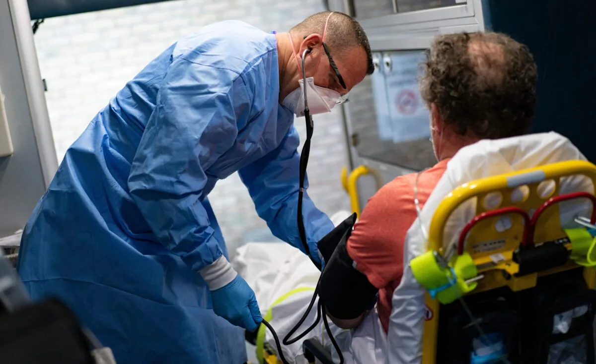A firefighter with Anne Arundel County Fire Department takes the blood pressure of a suspected COVID-19 patient as he is transported to the hospital, in Glen Burnie, Md., on May 3, 2020. (Alex Edelman/AFP via Getty Images)