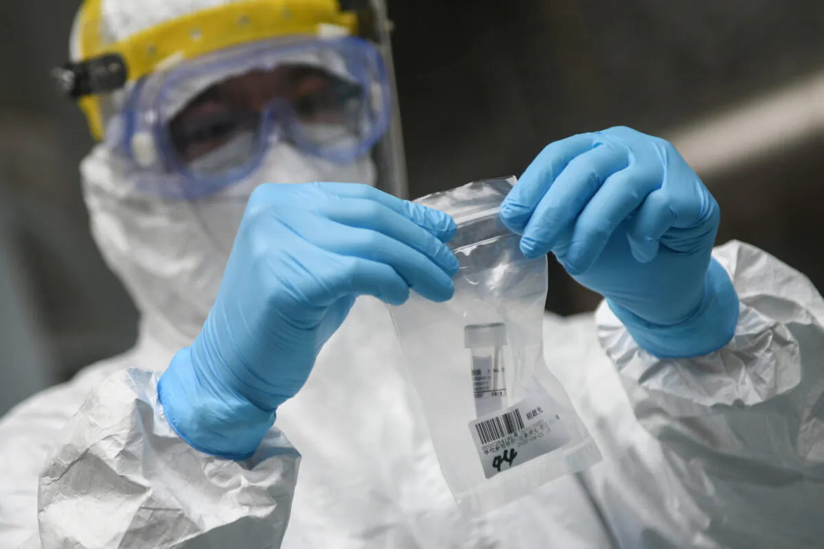 A medical staff member is collecting a biological sample at a middle school in Guangzhou, China on April 21, 2020. (STR/AFP via Getty Images)