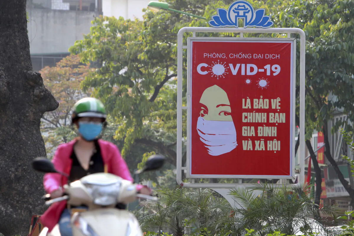 A motorcyclist drives past a poster calling people to take care of their health against the new coronavirus in Hanoi, Vietnam on April 14, 2020. (Hau Dinh/AP)