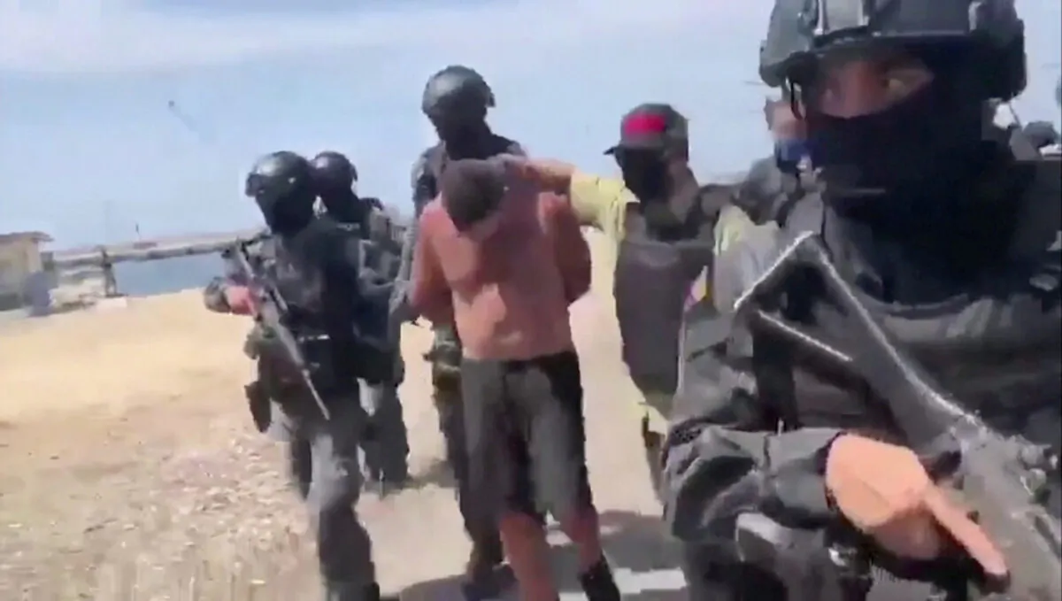 Venezuelan soldiers in balaclavas move a suspect from a helicopter after what Venezuelan authorities described was a "mercenary incursion", at an unknown location in this still frame obtained from Venezuelan government TV video, May 4, 2020. (Venezuelan Government TV/ Handout via Reuters TV)