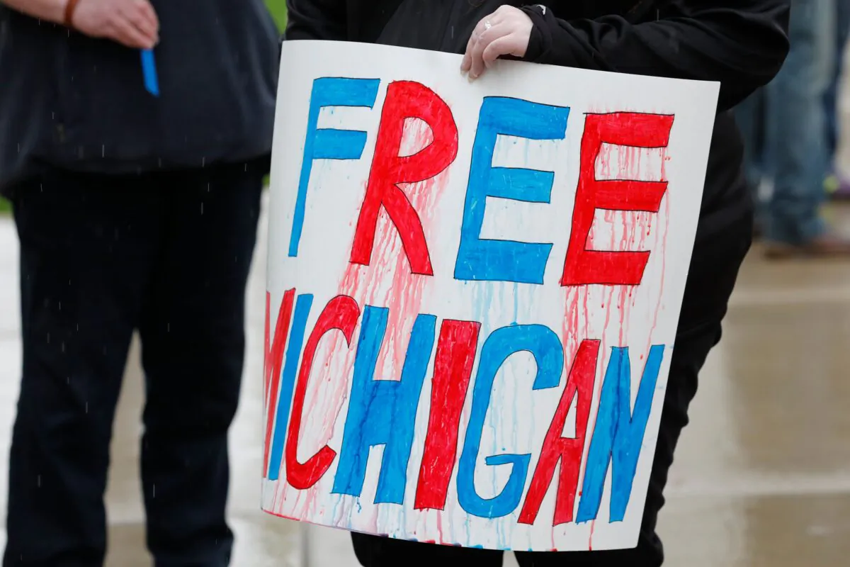 Demonstrators hold a "Free Michigan" sign as they take part in a rally demanding the reopening of businesses, in Lansing, Mich., on April 30, 2020. (Jeff Kowalsky/AFP/Getty Images)