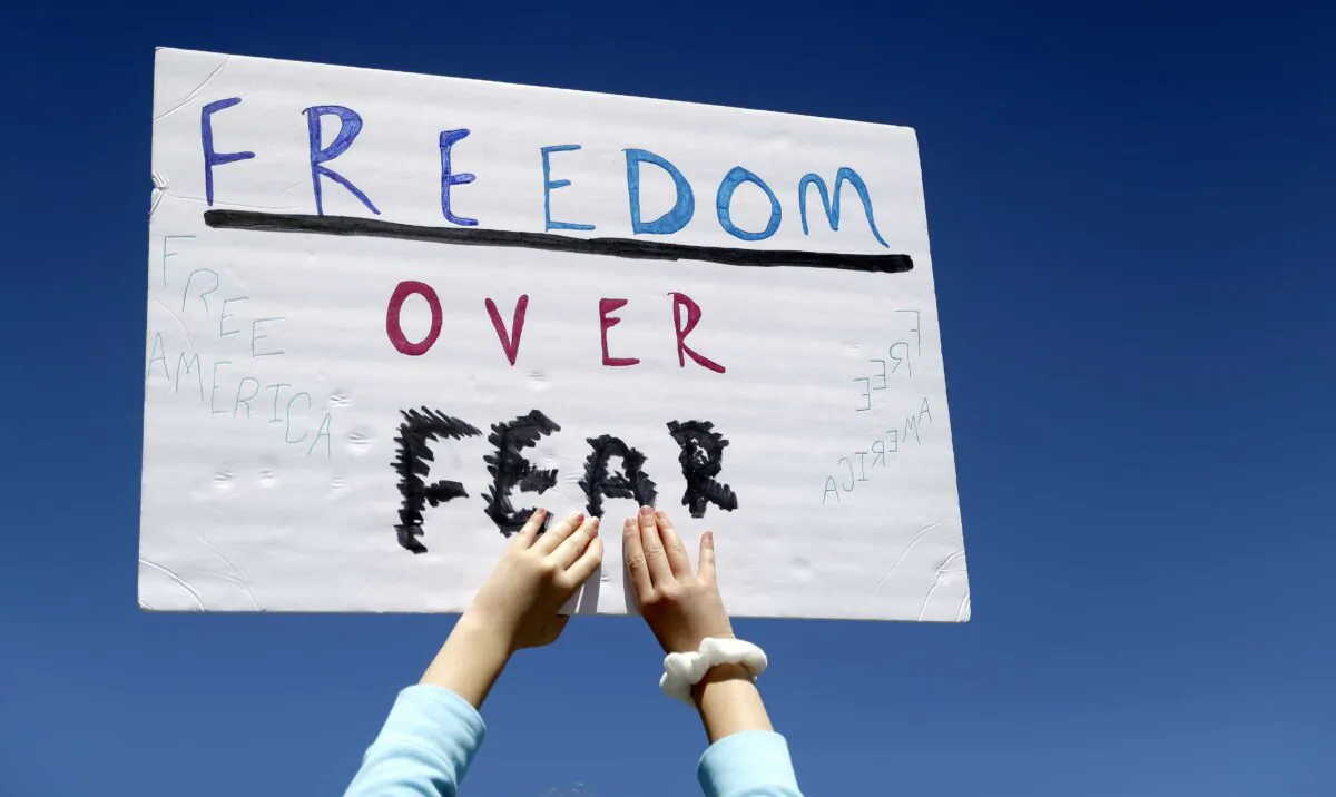 A person holds a sign while gathering with others to protest stay-at-home orders put into place due to the COVID-19 outbreak outside the Missouri Capitol in Jefferson City, Mo., on April 21, 2020. (Jeff Roberson/AP Photo)