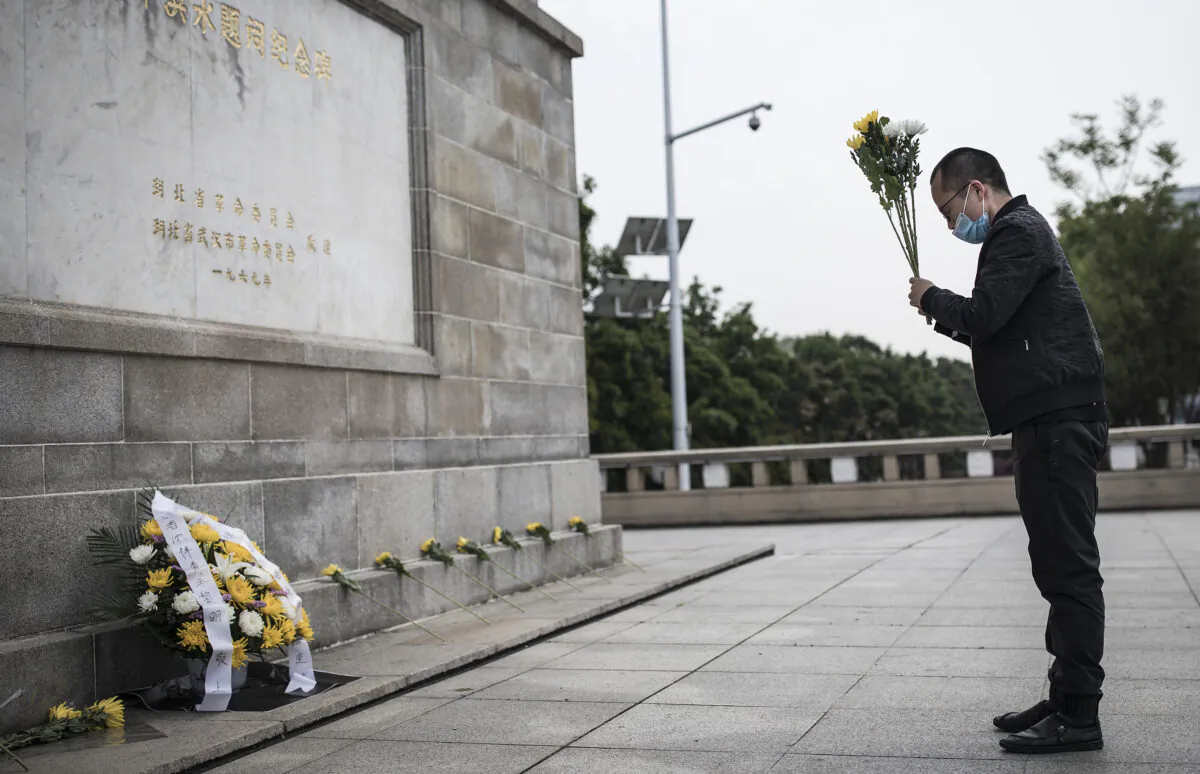 A resident presents flowers to martyrs who died in the fight against the CCP virus outbreak and compatriots who died of the disease in Wuhan, China on April 4, 2020. (Getty Images)