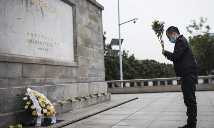 A resident presents flowers to martyrs who died in the fight against the CCP virus outbreak and compatriots who died of the disease in Wuhan, China on April 4, 2020. (Getty Images)