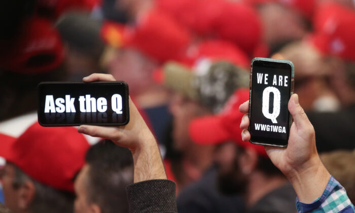People hold up smartphones with QAnon-related messages on display, at a rally in Las Vegas, Nevada, on Feb. 21, 2020. (Mario Tama/Getty Images)

