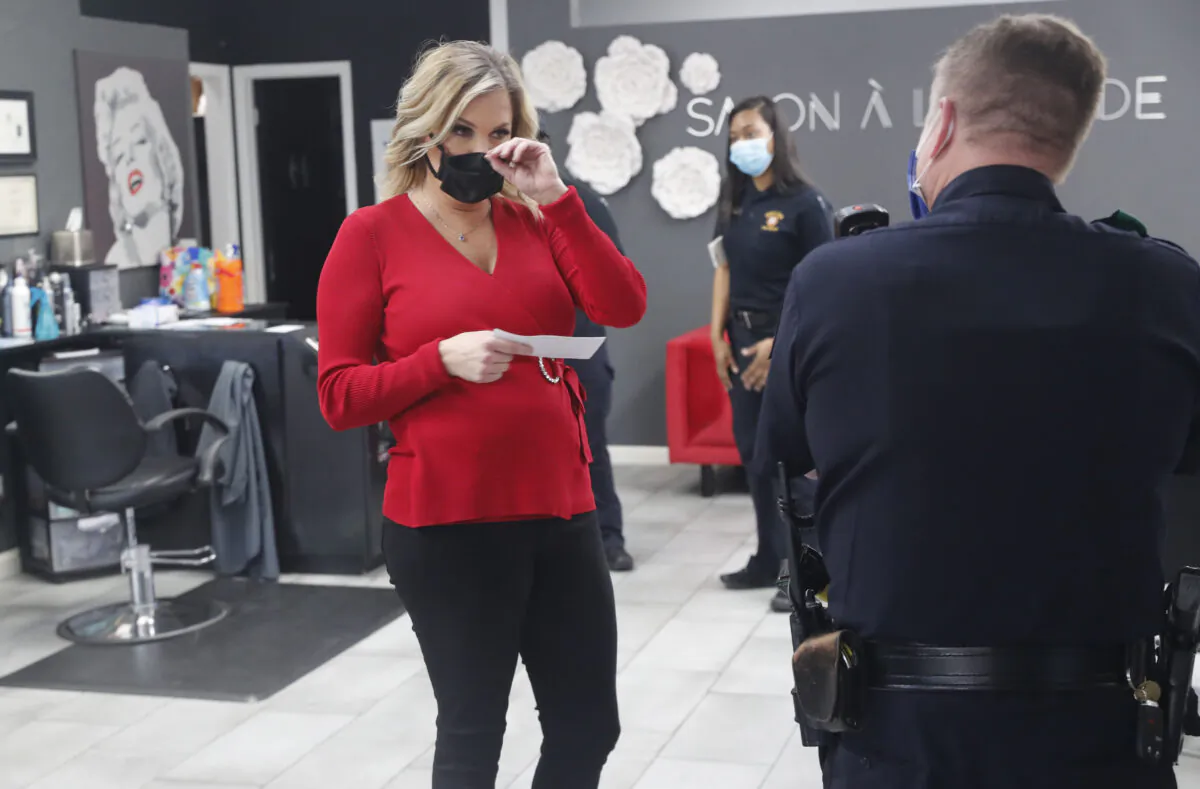 Salon owner Shelley Luther holds a citation and speaks with a Dallas police officer after she was cited for reopening her Salon A la Mode in Dallas, Texas, on April 24, 2020. (LM Otero/AP Photo)