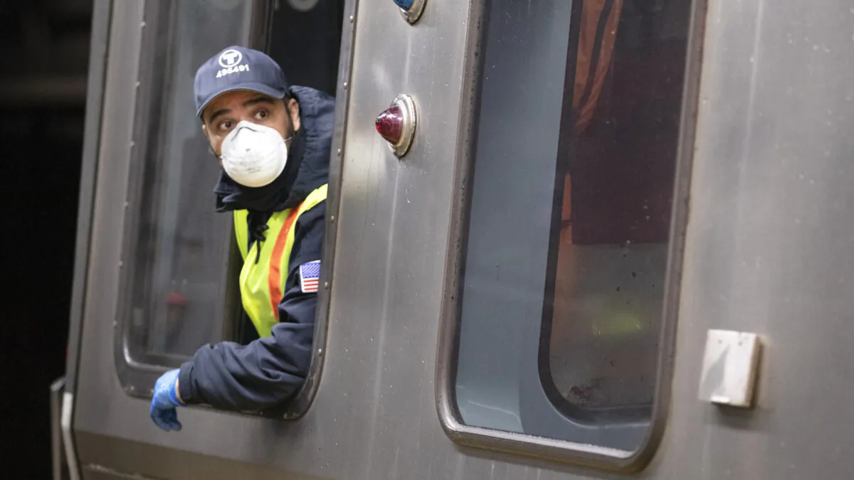 Train driver wearing a protective mask operates the doors of a Massachusetts Bay Transportation Authority's Blue Line subway car at Maverick Station in Boston on April 24, 2020. (Michael Dwyer/AP)