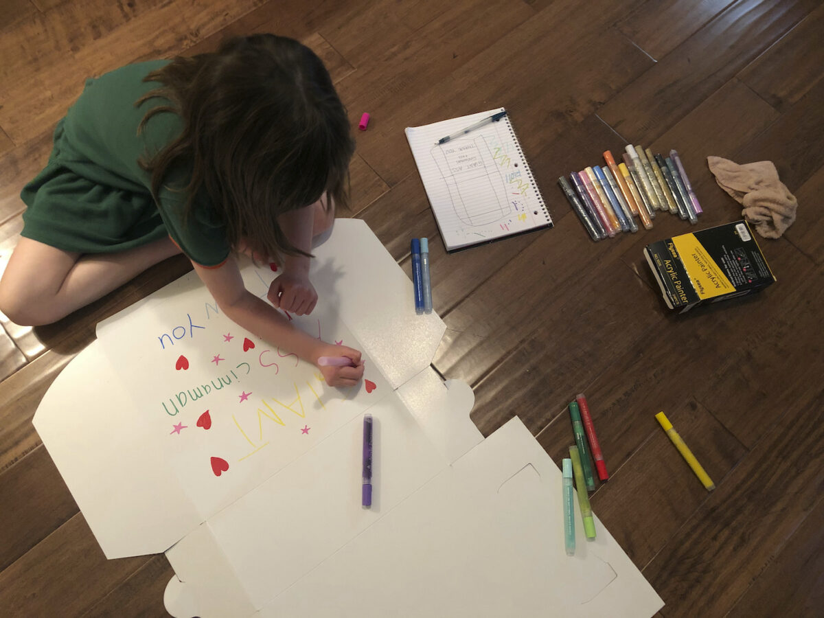 little girl decorates cinnamon roll box