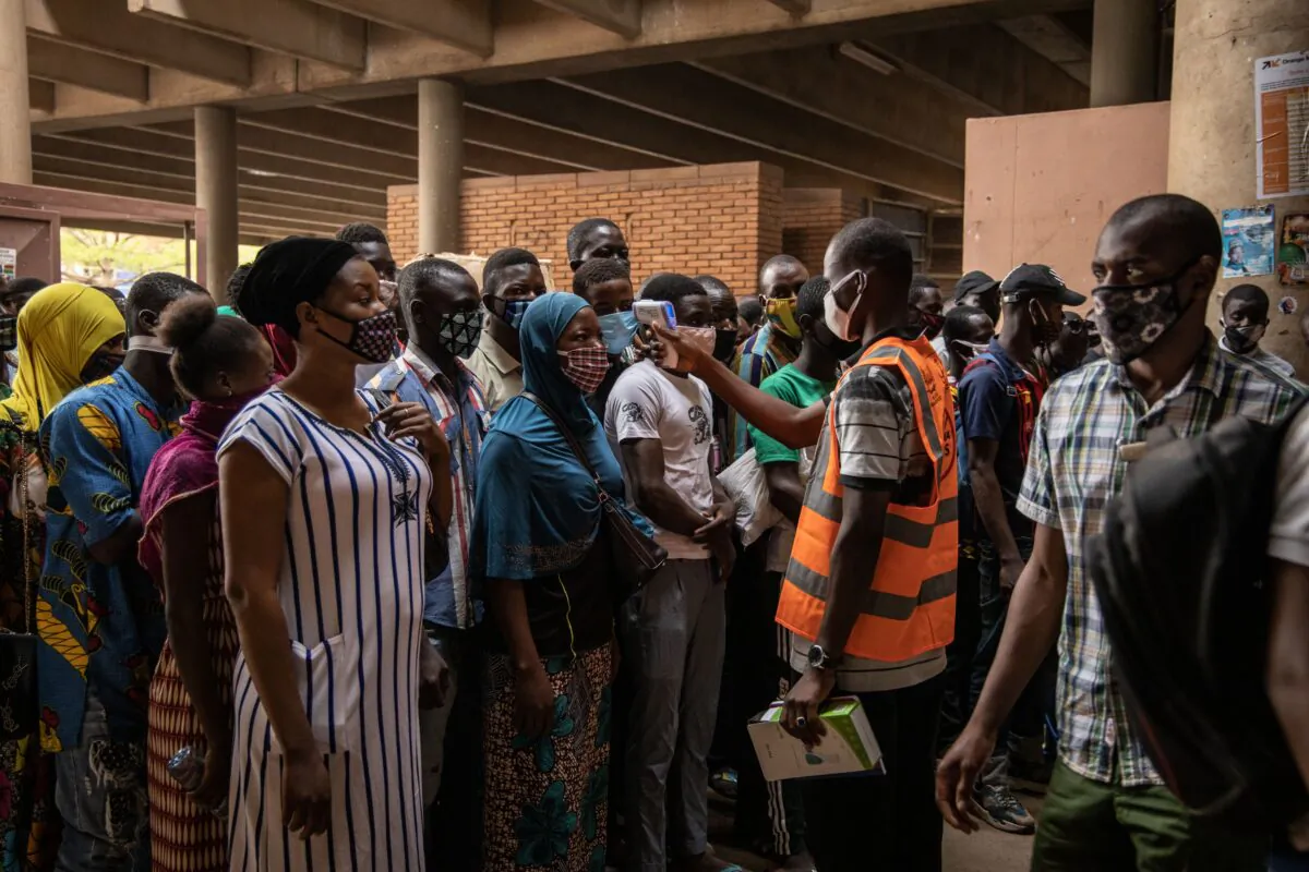 A communal agent measures the body temperature of traders at the opening of Rood Wokos great market in Ouagadougou, Burkina Faso, on April 20, 2020, after the market was closed since March 25, 2020, as a preventive measure against the spread of COVID-19. (Olympia de Maismont/AFP via Getty Images)