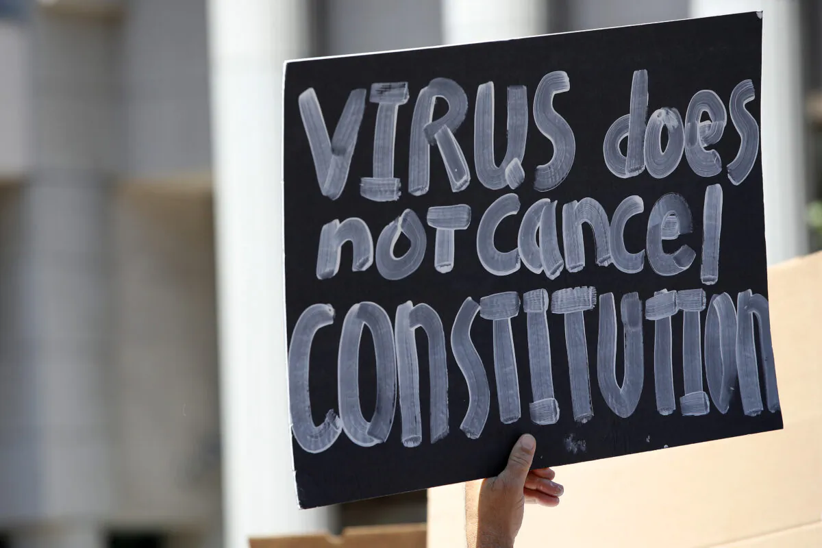 Activists hold signs and protest the California lockdown due to the coronavirus (Covid-19) pandemic, in San Diego, Calif., on May 1, 2020. The protesters demands included opening small businesses, churches as well as support for President Trump. (Sean M. Haffey/Getty Images)