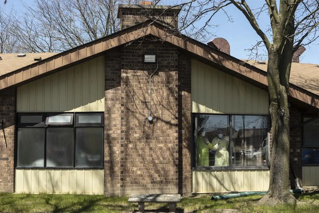 Staff members stand at a window as they watch a parade of well wishers as they drive through Orchard Villa Care home, in Pickering, Ont. on Saturday, April 25, 2020. (photo by Chris Young/The Canadian Press)
