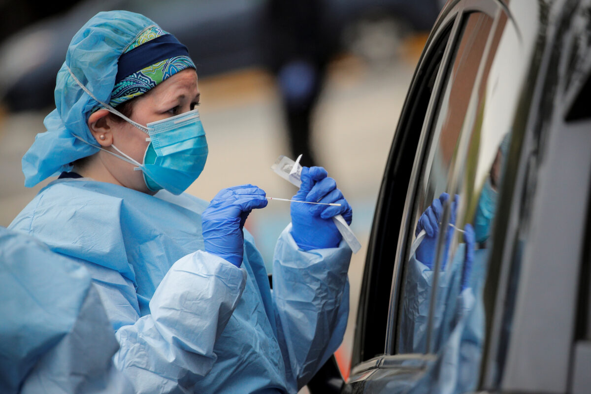Nurses work at a drive-thru testing site for the CCP virus