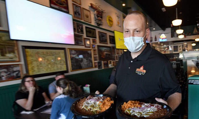 General manager Steven Hanson carries food to a table at Hussong's Cantina in Boca Park Fashion Village in Las Vegas on May 9, 2020. (Ethan Miller/Getty Images)
