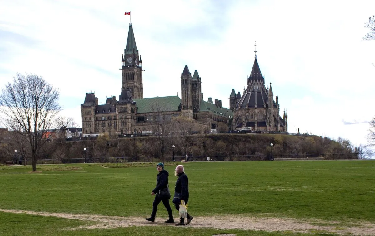 Parliament Hill is seen in the background as people walk through Major's Hill Park in Ottawa during the COVID-19 pandemic, on May 9, 2020. (The Canadian Press/Justin Tang)