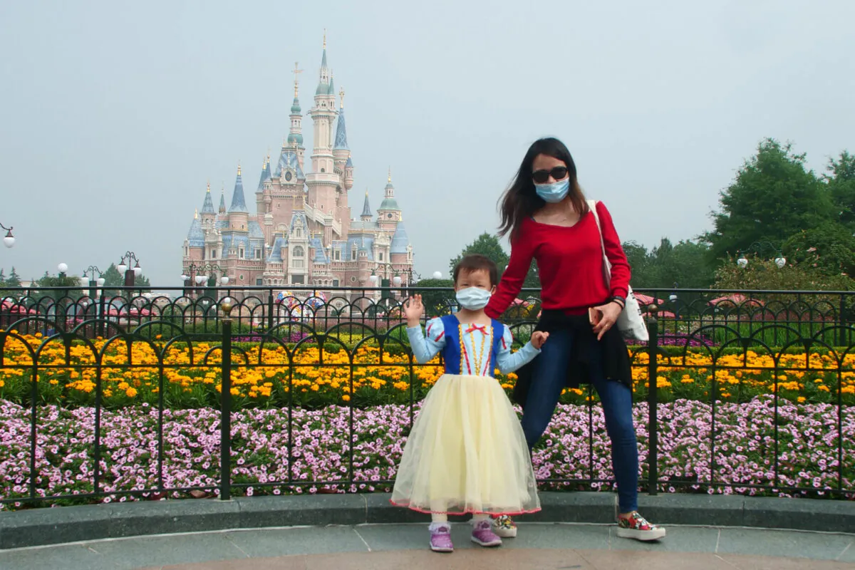 A young visitor, wearing a face mask, waves at the Disneyland theme park in Shanghai as it reopened after the COVID-19 pandemic closure, on May 11, 2020. (Sam McNeil/AP Photo)