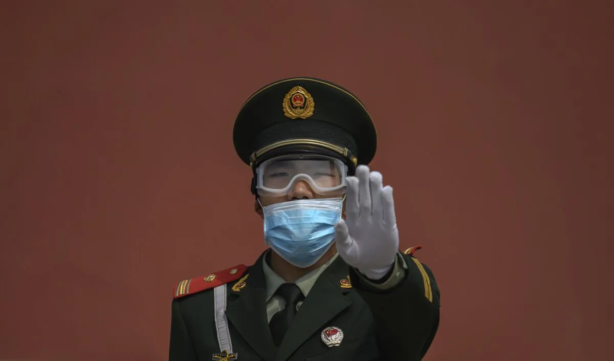 A Chinese paramilitary police officer gestures while standing guard at the entrance to the Forbidden City in Beijing, China on May 1, 2020. (Kevin Frayer/Getty Images)
