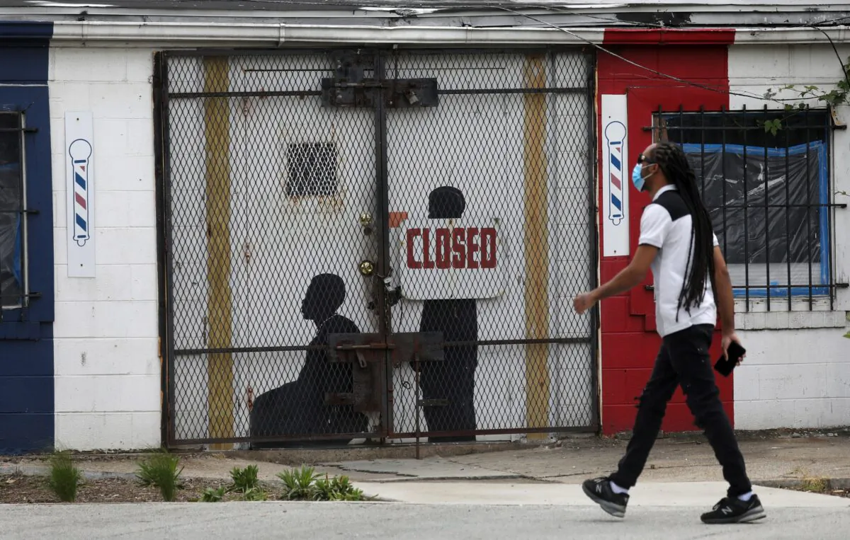 A pedestrian walks past a closed barber shop in Ward 7 as the CCP virus lockdown continues in Washington on May 8, 2020. (Leah Millis/Reuters)