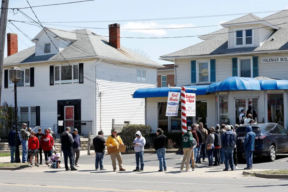 People wait in line to have their hair cut in front of the shop of Barber Karl Manke, who faces two misdemeanor charges for reopening his business despite state shutdown orders in Owosso, Mich., on May 12, 2020. (Jeff Kowalsky/AFP via Getty Images)