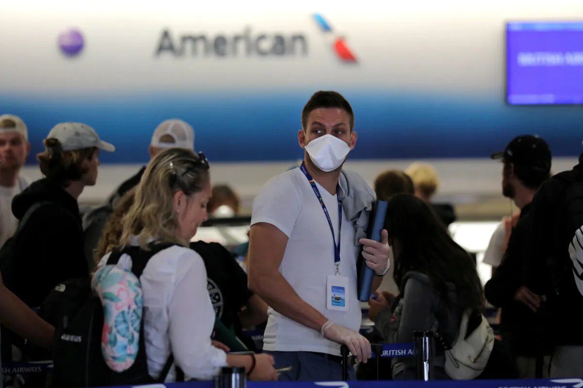 A passenger wearing a mask waits in line to check in for a flight as the Federal Aviation Administration (FAA) said it temporarily halted flights arriving at New York City airports and Philadelphia on Saturday after a trainee at the New York Air Route Traffic Control Center tested positive for coronavirus disease (COVID-19), at Miami International Airport, Miami, Fla., U.S., March 21, 2020. (Carlos Barria/Reuters)