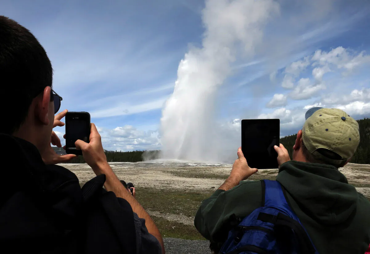  People use phones and tablets to photograph Old Faithful geyser erupting in Yellowstone National Park in Wyo., on May 16, 2014. (Jim Urquhart/File Photo/Reuters)
