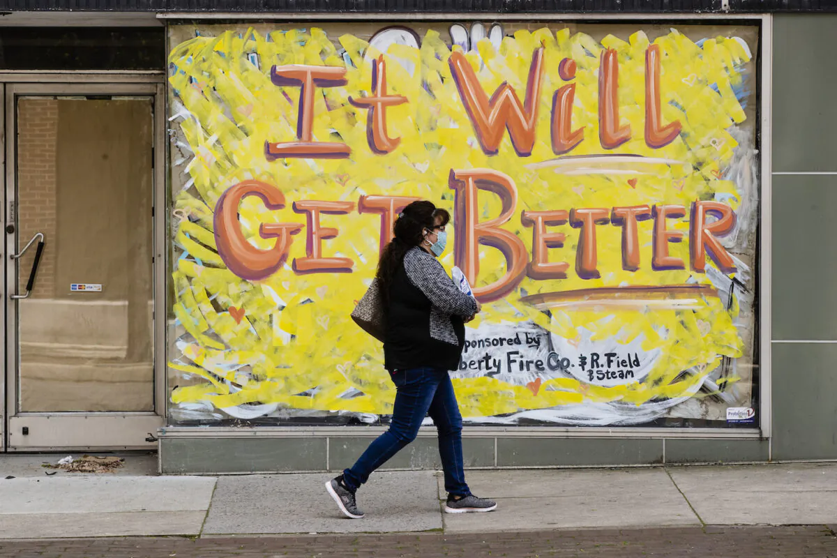 A person wearing a protective face mask as a precaution against COVID-19 walks by a closed storefront in Lebanon, Pa., on May 12, 2020. (AP Photo/Matt Rourke)