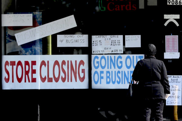 A woman looks at signs at a store closed