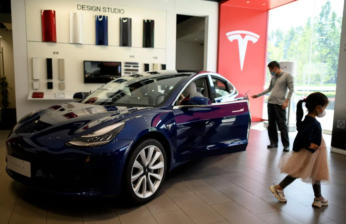 People looking at a Tesla car on display at a showroom in Beijing on May 10, 2020. (Noel Celis/AFP via Getty Images)