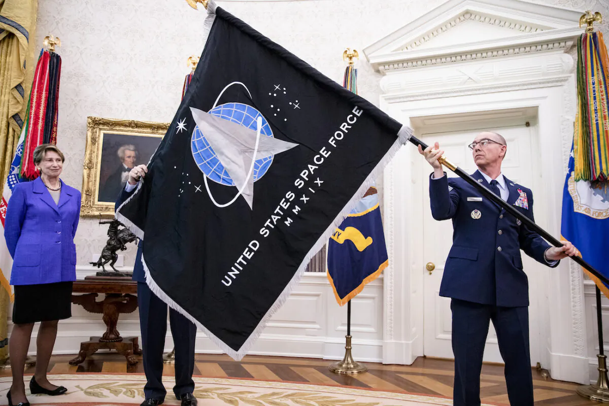 Gen. Jay Raymond (R), chief of Space Operations, and Chief Master Sergeant Roger Towberman (C), with Secretary of the Air Force Barbara Barrett, with the official flag of the United States Space Force in the Oval Office of the White House in Washington, on May 15, 2020. (Samuel Corum/Getty Images)