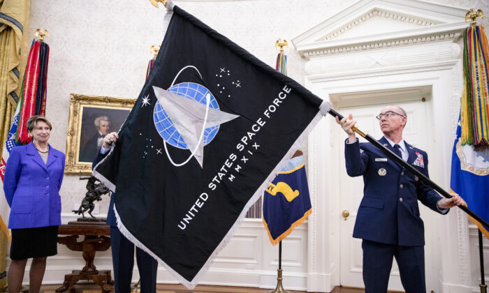 Gen. Jay Raymond (R), chief of Space Operations, and CMSgt Roger Towberman (L), with Secretary of the Air Force Barbara Barrett, present President Donald Trump with the official flag of the United States Space Force in the Oval Office of the White House in Washington, on May 15, 2020. (Samuel Corum-Pool/Getty Images)