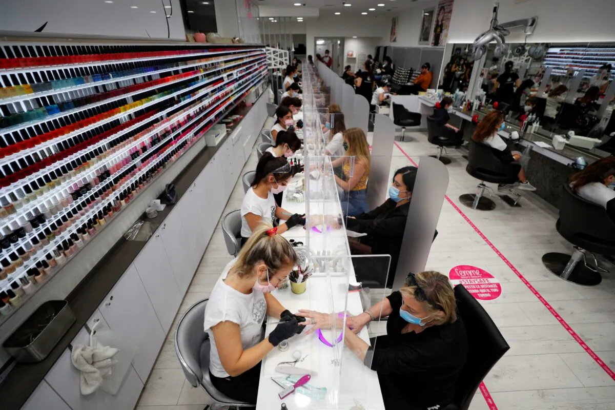 Women wearing protective masks work on the nails of customers at a beauty salon, as Italy eases some of the lockdown measures put in place during the CCP virus disease (COVID-19) outbreak, in Rome, Italy, on May 18, 2020. (Guglielmo Mangiapane/Reuters)