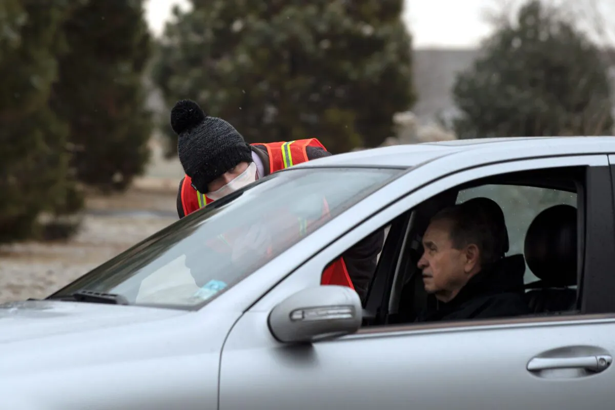 A health worker with the Colorado Department of Health and Environment talks with a man who is waiting for a drive-up testing site for the CCP virus to open in Denver, Colo. on March 13, 2020. (Jason Connolly/AFP via Getty Images)