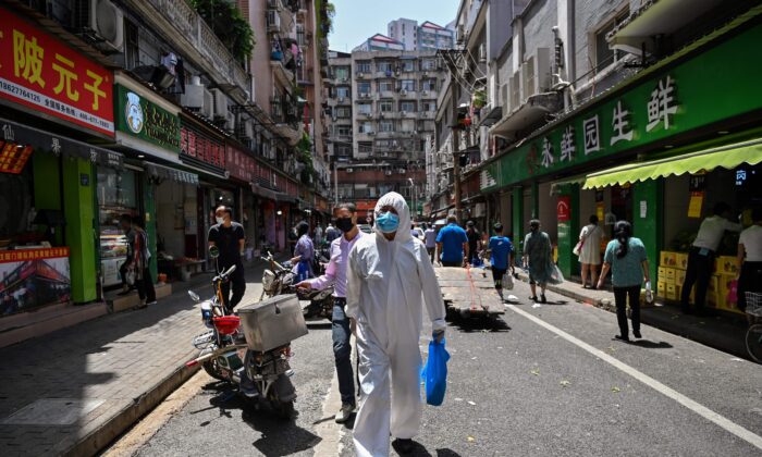 A man wearing protective gear walks past shops in Wuhan, in Chinas central Hubei province on May 18, 2020. (Hector Retamal/AFP via Getty Images)