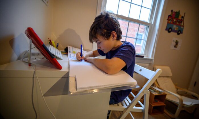 Colin, 10, whose school was closed following the CCP virus outbreak, does school exercises at home in Washington on March 20, 2020. (Eric Baradat/AFP via Getty Images)
