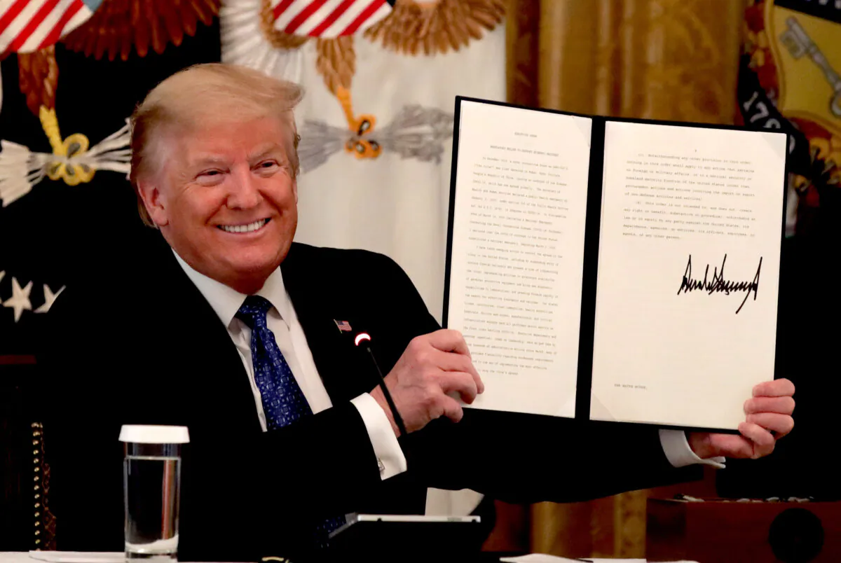 President Donald Trump holds up a copy of an executive order he signed on DOT deregulation, during a meeting with his cabinet in the East Room of the White House on May 19, 2020. (Alex Wong/Getty Images)