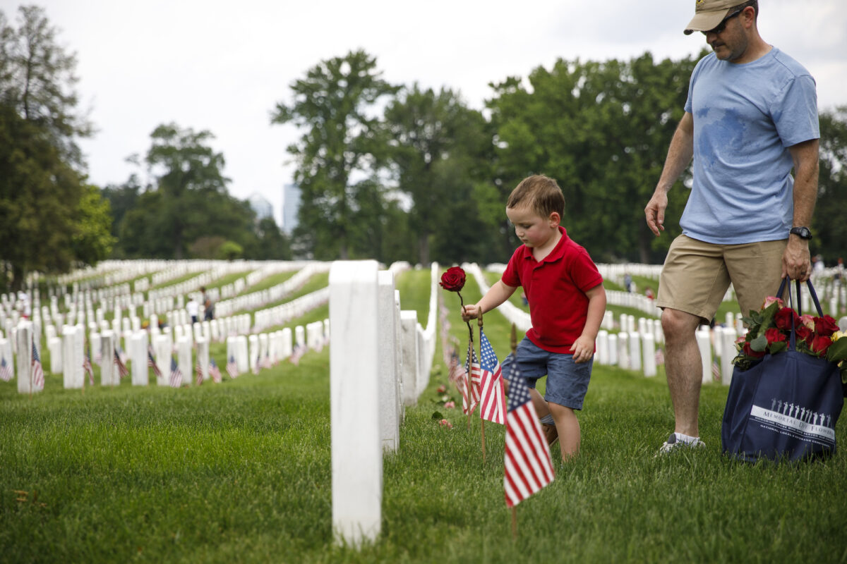 Matthew Murphy, 4, places a rose on a tombstone beside his father, Kevin Murphy, of Springfield, Va., during a volunteer event at Arlington National Cemetery ahead of Memorial Day on May 26, 2019. (Tom Brenner/Getty Images)