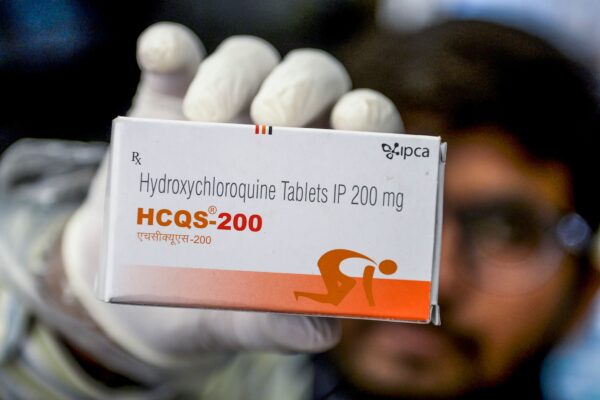 A pharmacist displaying a box of hydroxychloroquine