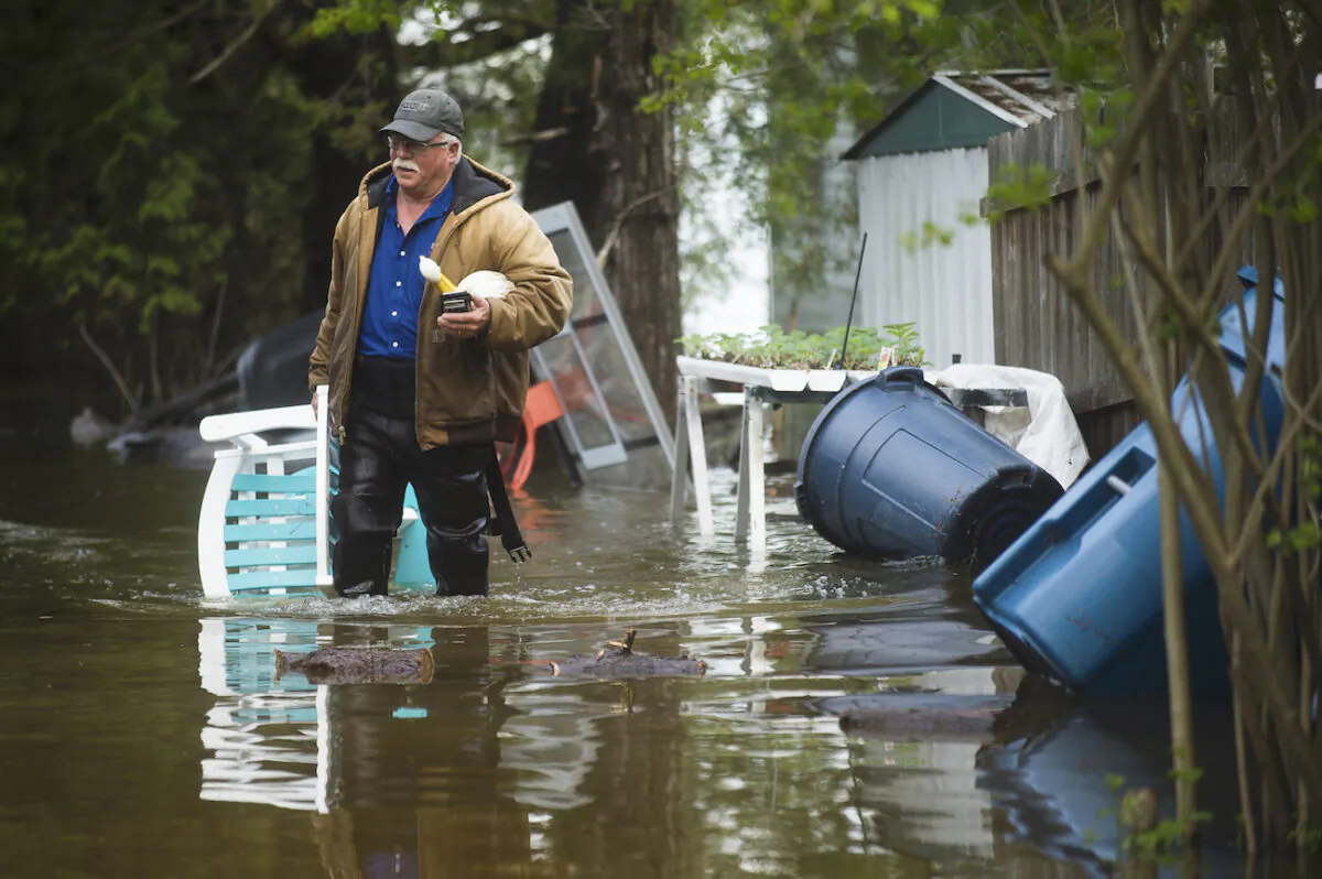 A man brings a chair to the front of his house from the back yard, wading through floodwater in Edenville, Mich., on May 19, 2020. (Katy Kildee/Midland Daily News via AP)