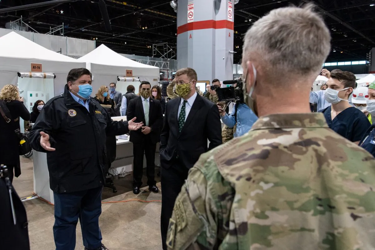 Gov. J.B. Pritzker (L) and U.S. Army Secretary Ryan McCarthy meet with members of the Illinois National Guard, medical professionals and construction workers who helped build and staff the COVID-19 alternate care facility at McCormick Place in Chicago, Ill., on April 17, 2020. (Tyler LaRiviere/Getty Images)