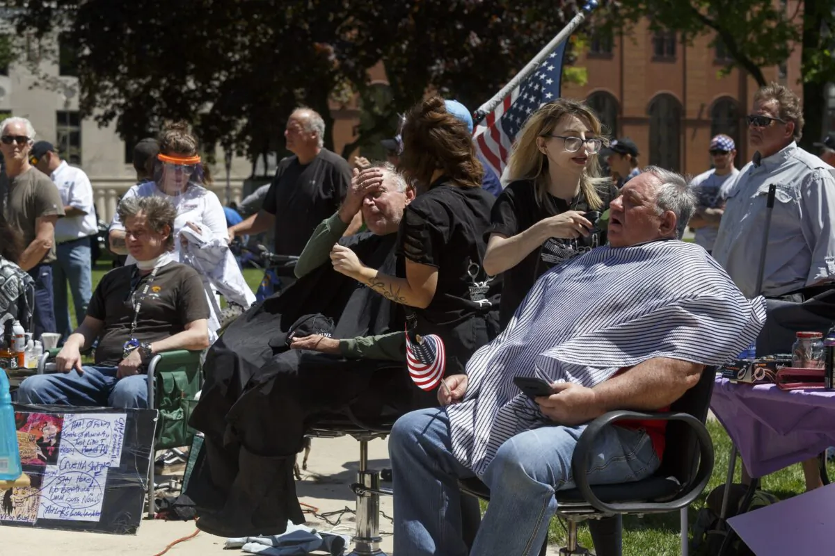 Barbers cut hair for free near the steps of the state Capitol during Operation Haircut in Lansing, Mich., on May 20, 2020. (Elaine Cromie/Getty Images)