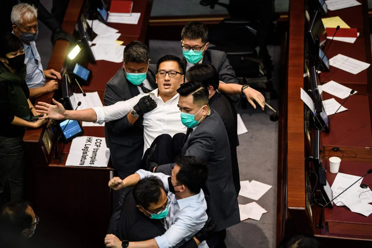 Pan-democratic politician, Lam Cheuk-ting (C) is removed by security after throwing papers torn from the Legco rulebook during a scuffle between pro-democracy and pro-Beijing lawmakers at the House Committee's election of chairpersons, at the Legislative Council in Hong Kong on May 18, 2020. (Anthony Wallace/AFP via Getty Images)