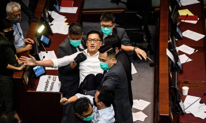 Pan-democratic politician, Lam Cheuk-ting (C) is removed by security after throwing papers torn from the Legco rulebook during a scuffle between pro-democracy and pro-Beijing lawmakers at the House Committee's election of chairpersons, at the Legislative Council in Hong Kong on May 18, 2020. (Anthony Wallace/AFP via Getty Images)